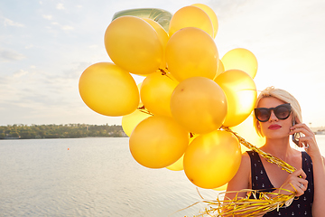 Image showing Young woman with many golden balloons.