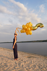 Image showing Young woman with many golden balloons.