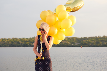 Image showing Young woman with many golden balloons.