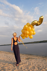 Image showing Young woman with many golden balloons.