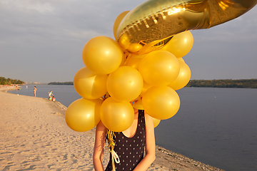 Image showing Young woman with many golden balloons.