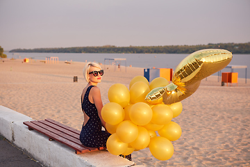 Image showing Young woman with many golden balloons.