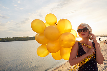 Image showing Young woman with many golden balloons.