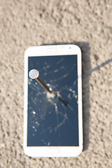 Image showing metal nail and smartphone with a broken screen over the stone surface. The concept of strength.