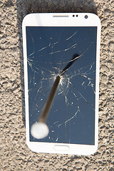 Image showing metal nail and smartphone with a broken screen over the stone surface. The concept of strength.