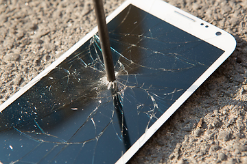 Image showing metal nail and smartphone with a broken screen over the stone surface. The concept of strength.