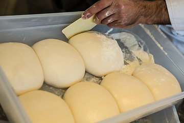 Image showing Small balls of fresh homemade pizza dough on floured wooden boar