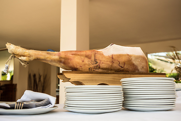 Image showing Chef slices serrano ham. Jamon Serrano. Typical Spanish delicatessen prosciutto.