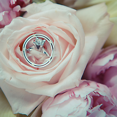 Image showing wedding rings lie on a beautiful bouquet as bridal accessories