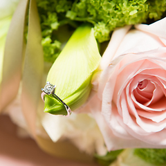 Image showing wedding rings lie on a beautiful bouquet as bridal accessories.