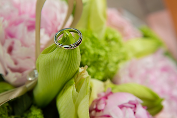 Image showing wedding rings lie on a beautiful bouquet as bridal accessories