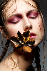 Image showing beautiful girl with modern braids and metal flower in mouth