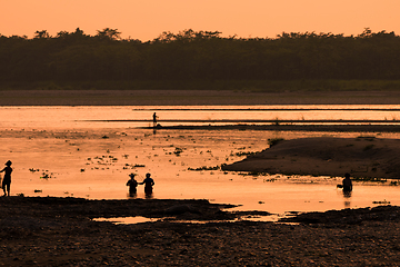 Image showing Asian women fishing in the river, silhouette at sunset