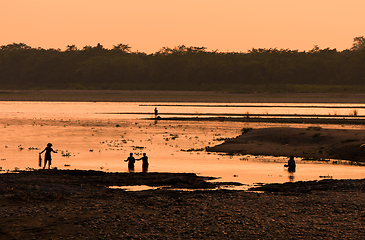 Image showing Asian women fishing in the river, silhouette at sunset