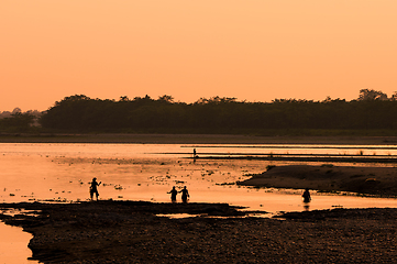 Image showing Asian women fishing in the river, silhouette at sunset