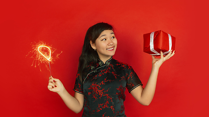 Image showing Happy Chinese New Year. Asian young girls\'s portrait isolated on red background