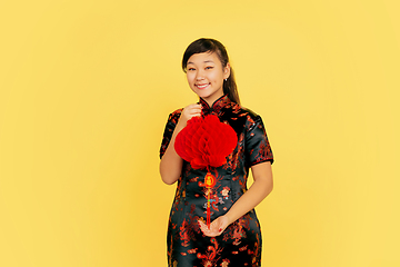 Image showing Happy Chinese New Year. Asian young girls\'s portrait isolated on yellow background