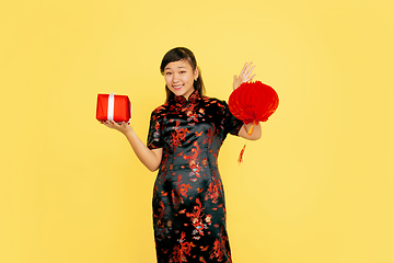 Image showing Happy Chinese New Year. Asian young girls\'s portrait isolated on yellow background