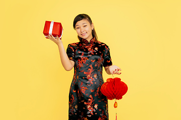 Image showing Happy Chinese New Year. Asian young girls\'s portrait isolated on yellow background