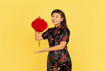 Image showing Happy Chinese New Year. Asian young girls\'s portrait isolated on yellow background