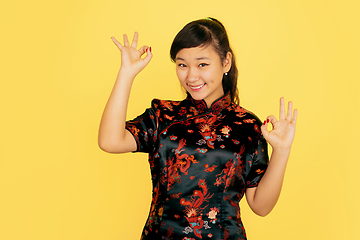 Image showing Happy Chinese New Year. Asian young girls\'s portrait isolated on yellow background