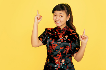 Image showing Happy Chinese New Year. Asian young girls\'s portrait isolated on yellow background