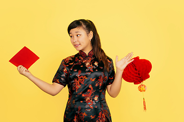 Image showing Happy Chinese New Year. Asian young girls\'s portrait isolated on yellow background