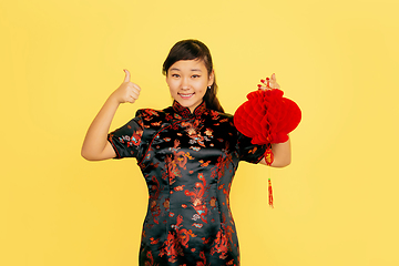 Image showing Happy Chinese New Year. Asian young girls\'s portrait isolated on yellow background