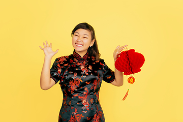 Image showing Happy Chinese New Year. Asian young girls\'s portrait isolated on yellow background