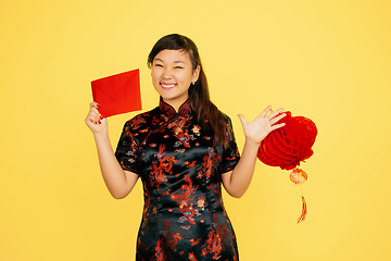 Image showing Happy Chinese New Year. Asian young girls\'s portrait isolated on yellow background