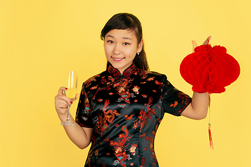 Image showing Happy Chinese New Year. Asian young girls\'s portrait isolated on yellow background