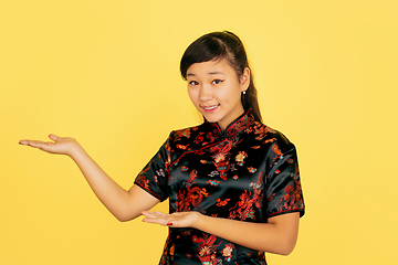 Image showing Happy Chinese New Year. Asian young girls\'s portrait isolated on yellow background