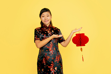 Image showing Happy Chinese New Year. Asian young girls\'s portrait isolated on yellow background