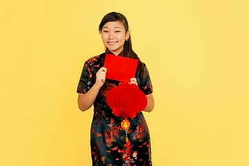 Image showing Happy Chinese New Year. Asian young girls\'s portrait isolated on yellow background