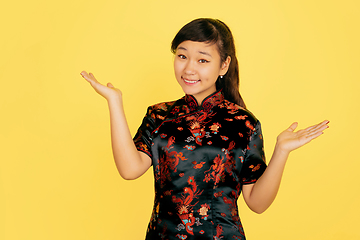 Image showing Happy Chinese New Year. Asian young girls\'s portrait isolated on yellow background