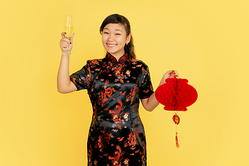 Image showing Happy Chinese New Year. Asian young girls\'s portrait isolated on yellow background