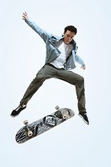 Image showing Caucasian young skateboarder riding isolated on a white background