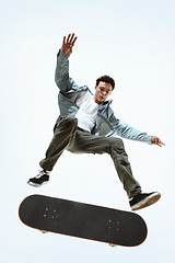 Image showing Caucasian young skateboarder riding isolated on a white background