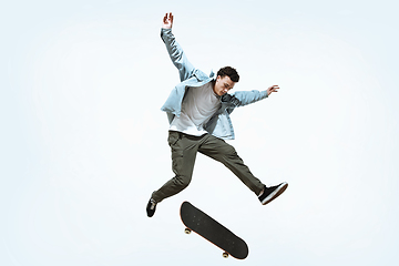 Image showing Caucasian young skateboarder riding isolated on a white background