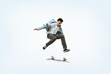 Image showing Caucasian young skateboarder riding isolated on a white background