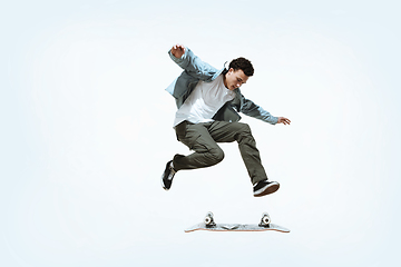 Image showing Caucasian young skateboarder riding isolated on a white background