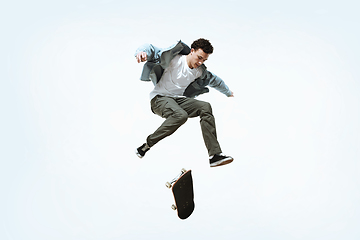 Image showing Caucasian young skateboarder riding isolated on a white background