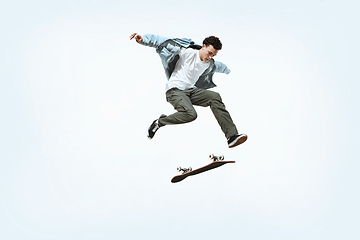 Image showing Caucasian young skateboarder riding isolated on a white background