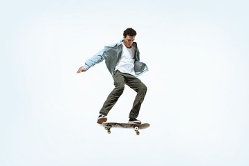 Image showing Caucasian young skateboarder riding isolated on a white background