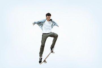 Image showing Caucasian young skateboarder riding isolated on a white background