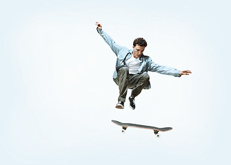 Image showing Caucasian young skateboarder riding isolated on a white background