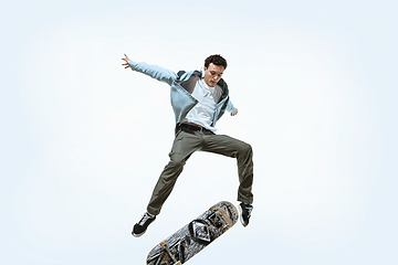 Image showing Caucasian young skateboarder riding isolated on a white background