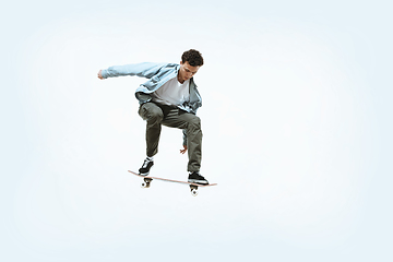 Image showing Caucasian young skateboarder riding isolated on a white background