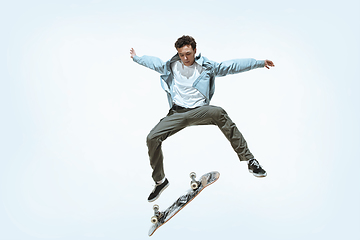 Image showing Caucasian young skateboarder riding isolated on a white background