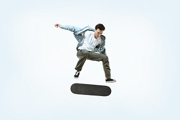 Image showing Caucasian young skateboarder riding isolated on a white background